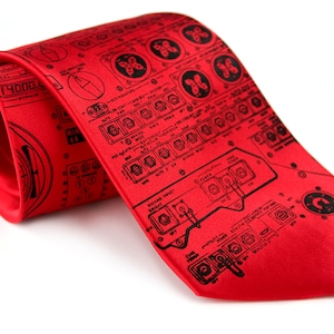 May include: A red silk tie featuring a black printed design of a cockpit control panel. The design includes various dials, switches, and labels.
