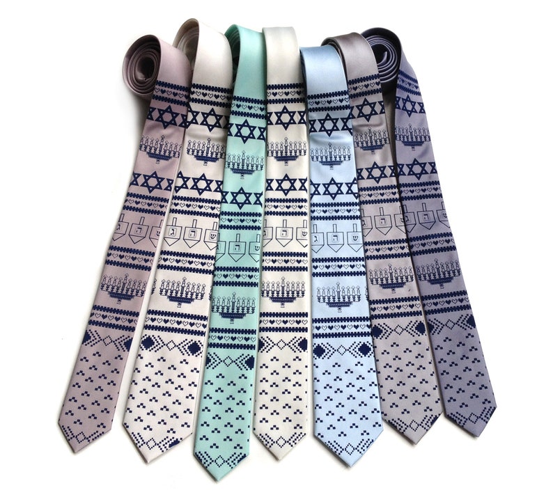 May include: A collection of seven neckties in various pastel colors, each featuring a repeating pattern of a Star of David, menorah, and dreidel. The ties are arranged on a white background.