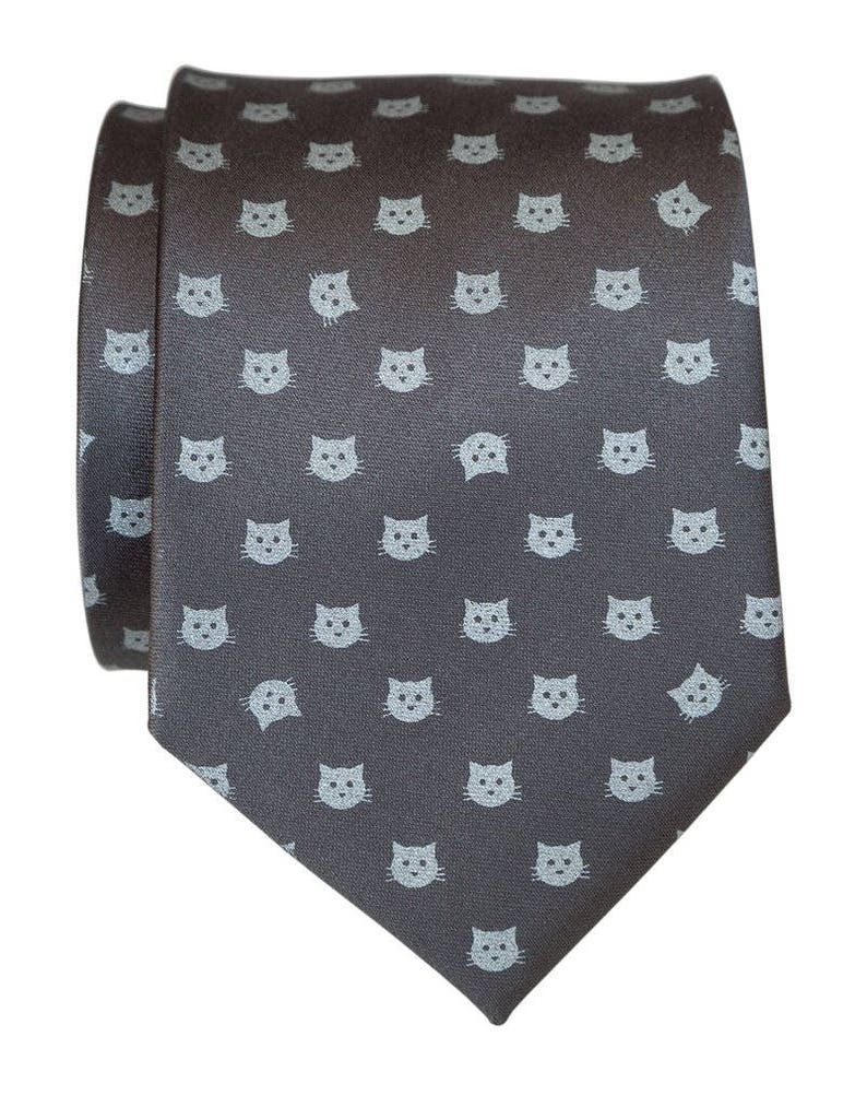 Puede incluir: Una corbata gris oscuro con un patr&oacute;n repetido de caras de gato azul claro.