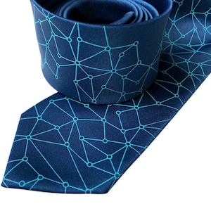 Puede incluir: Una corbata azul oscuro con un patrón geométrico de líneas y puntos azul turquesa.