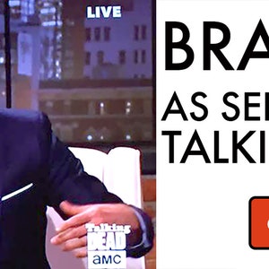 May include: A man wearing a blue suit and a tie with a brain pattern. The tie is advertised as "Brain Tie as seen on The Walking Dead". The text "Get Your Own!" is on a red button.