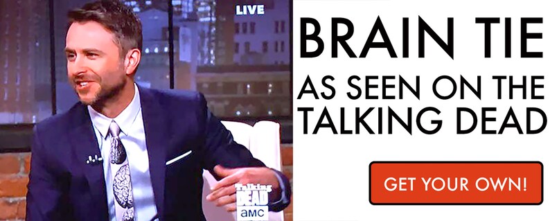 May include: A man wearing a blue suit and a tie with a brain pattern. The tie is advertised as "Brain Tie as seen on The Walking Dead". The text "Get Your Own!" is on a red button.