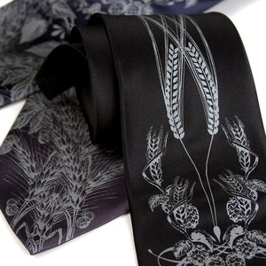 May include: Two black silk ties with a silver wheat and hop design. The ties are folded and arranged on a white background.
