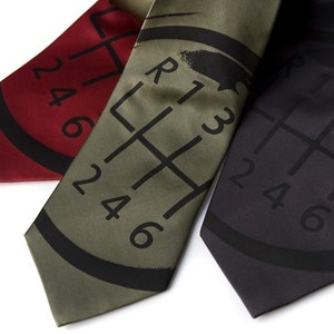 May include: Three silk ties with a gear shift pattern printed on them. The ties are in red, green, and black.