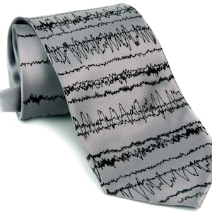 May include: A gray silk tie with a black and white pattern of an electrocardiogram waveform.