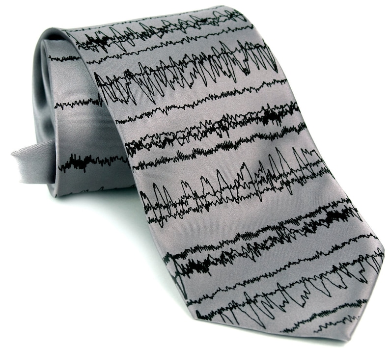 May include: A gray silk tie with a black and white pattern of an electrocardiogram waveform.