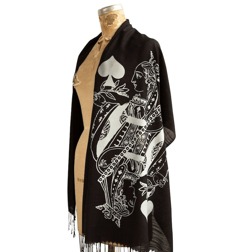 May include: Black silk scarf with a white print of the Queen of Spades playing card. The Queen is wearing a crown and holding a sword.