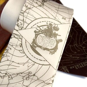 May include: A white silk tie with a brown and gold map design. The map features a compass rose and the text "Aviation Navigation Stream 1200".