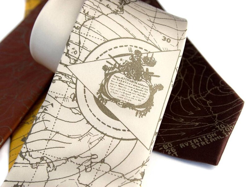 May include: A white silk tie with a brown and gold map design. The map features a compass rose and the text "Aviation Navigation Stream 1200".