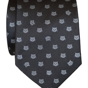 Puede incluir: Una corbata de seda gris oscuro con un patr&oacute;n repetido de caras de gato gris claro.