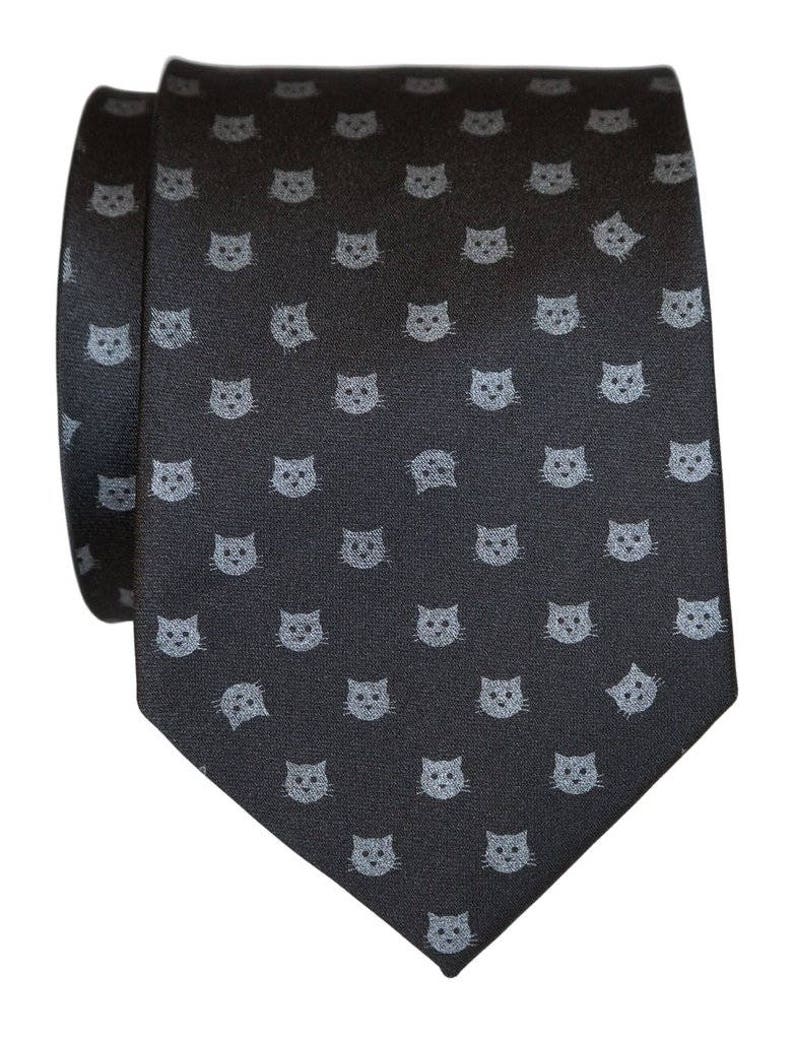 Puede incluir: Una corbata de seda gris oscuro con un patr&oacute;n repetido de caras de gato gris claro.