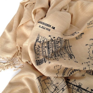Peut inclure: Une écharpe en soie beige avec un motif imprimé noir et blanc d'un brevet vintage pour une machine à écrire. Le brevet a été délivré le 3 juillet 1933. Le texte sur l'écharpe est "AUSGEGEBEN AM 3. JULI 1933" et "PATE SCHRIFT 579555 ALASSE 42 GRUPPE 14".