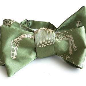 May include: A green bow tie with a white dinosaur skeleton print.