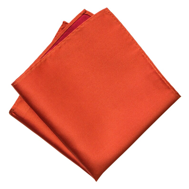 Op de afbeelding: Een gevouwen oranje zijden zakdoek. De vierkant is dubbelgevouwen en de randen zijn zichtbaar.