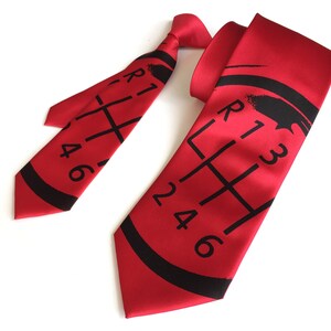 May include: Red silk tie with a black printed gear shift pattern. The pattern includes the numbers 1, 2, 3, 4, 5, and 6.