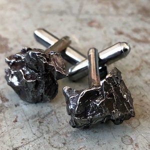 Handmade authentic irony meteorite cufflinks with silver hardware on a beige surface, by Detroit's Cyberoptix Tie Lab.