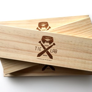 May include: Three wooden boxes stacked on top of each other. The top box has a logo that says "Tie Lab" with a tie and collar design. The logo also says "Hand Made" and "Produced in Detroit".