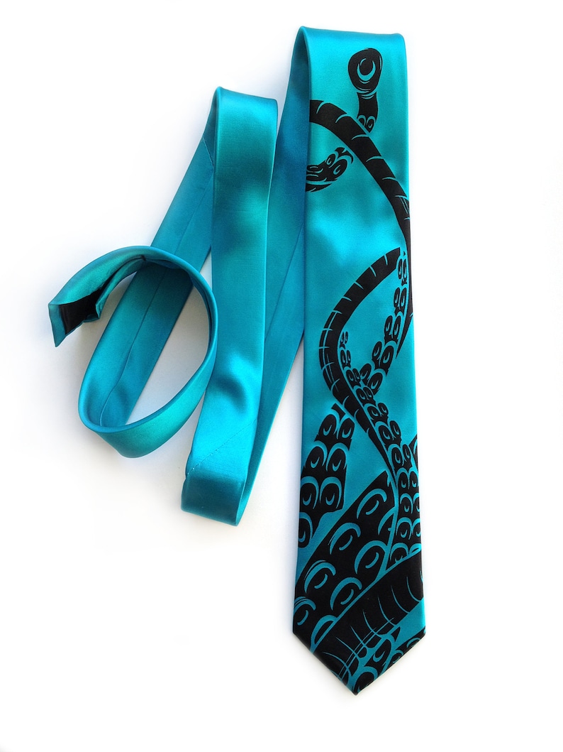 Puede incluir: Una corbata de seda azul turquesa con un dise&ntilde;o de pulpo negro. El pulpo se representa con sus tent&aacute;culos envueltos alrededor de la corbata.