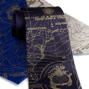 May include: Three silk neckties with a map design. The ties are navy blue, dark gray, and light gray. The maps are printed in gold. The navy blue tie has the text "AVIATION STREAM" printed on it. The dark gray tie has the text "30" printed on it.