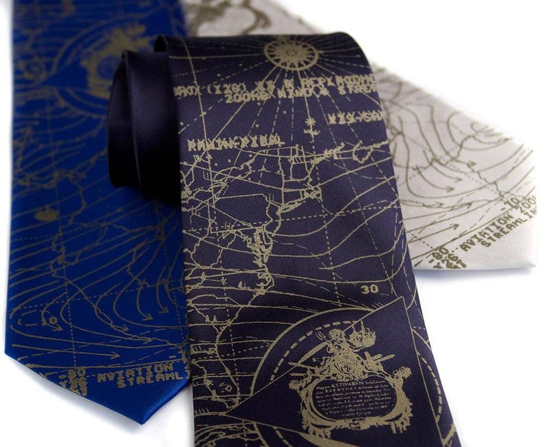 May include: Three silk neckties with a map design. The ties are navy blue, dark gray, and light gray. The maps are printed in gold. The navy blue tie has the text "AVIATION STREAM" printed on it. The dark gray tie has the text "30" printed on it.