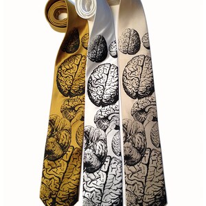 May include: Three silk neckties with a black and white brain print. The ties are in gold, white, and beige.