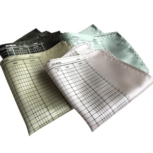 May include: Four silk pocket squares with a printed journal design. The squares are in shades of green, white, and light blue.