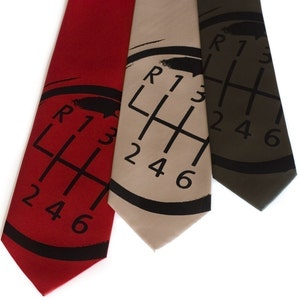 May include: Three silk ties with a black and white gear shift pattern. The ties are red, beige, and dark green.