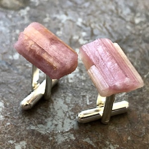 Könnte beinhalten: Ein Paar Manschettenknöpfe mit rosafarbenen und weißen Turmalin-Edelsteinen, die in Silber gefasst sind.