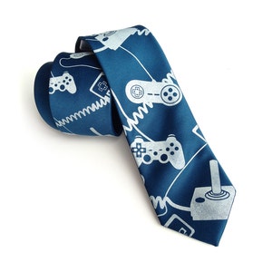 May include: A blue silk tie with a white pattern of video game controllers and joysticks.