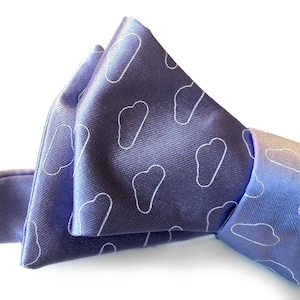 Peut inclure: Gros plan sur un nœud papillon bleu avec un motif de nuages blancs. Le nœud papillon est fait d'une matière soyeuse et est noué. Le fond est blanc.