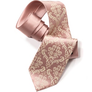 May include: A pink satin tie with a cream-colored damask pattern. The tie is tied in a knot and the ends are hanging down.
