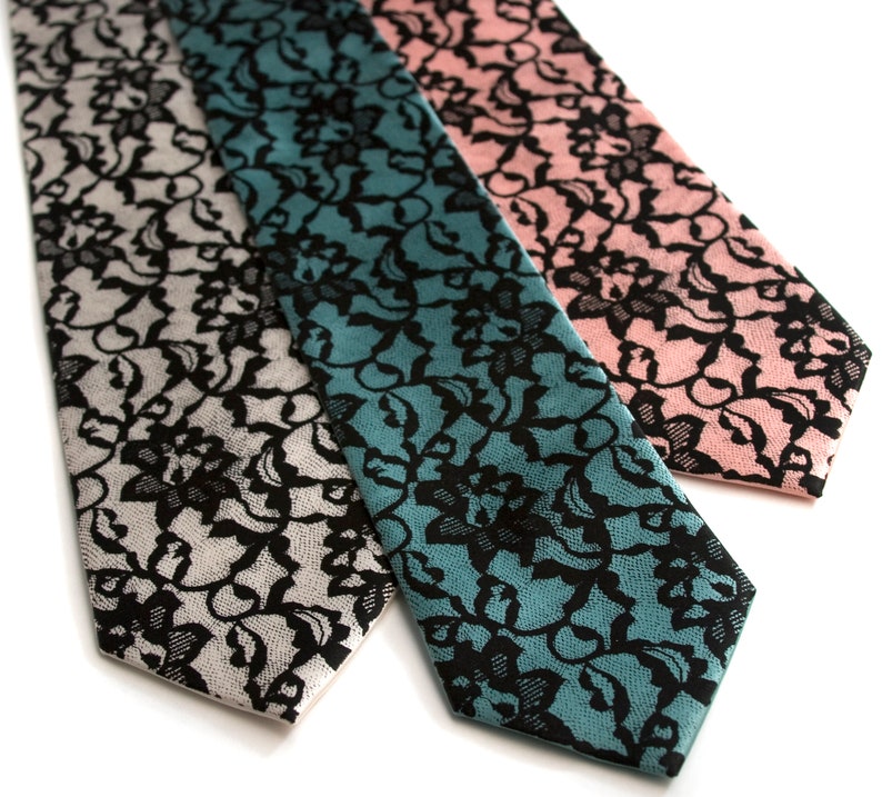 May include: Three silk neckties with a black lace pattern on a white, teal, and pink background.