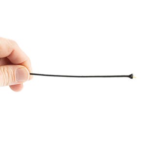 Könnte beinhalten: Nahaufnahme eines schwarzen Kabels, das von einer Hand gehalten wird. Das Kabel ist dünn und scheint aus einem gewebten Material zu bestehen.