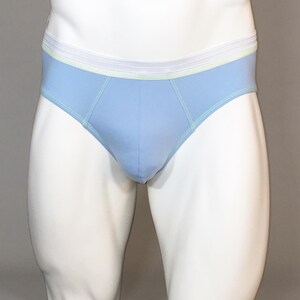 May include: Light blue briefs with a white and light green waistband. The briefs are displayed on a white mannequin. The seams are accented with light green stitching. The briefs are made of a soft material.