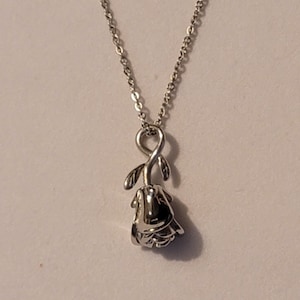 May include: A silver chain necklace with a silver rose pendant. The rose is detailed with leaves and a stem.