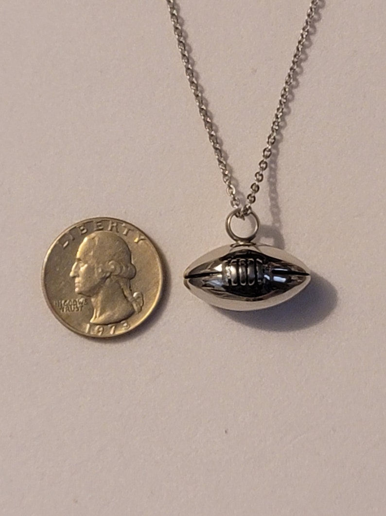 Pu&ograve; includere: Una collana con catena d'argento con un ciondolo a forma di pallone da calcio in argento. Il ciondolo &egrave; circa delle dimensioni di una moneta da 25 centesimi.