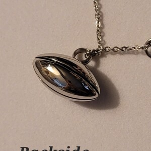 Pu&ograve; includere: Una collana con catena d'argento con un ciondolo d'argento a forma di pallone da calcio. Il ciondolo &egrave; liscio e lucido.