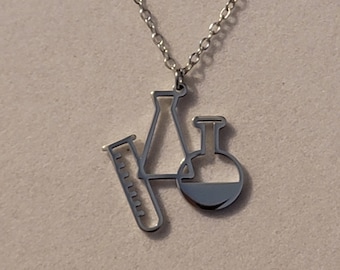 May include: A silver necklace with a pendant shaped like a beaker, flask, and graduated cylinder.