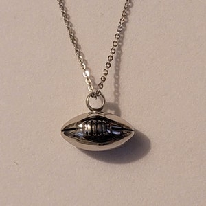 Pu&ograve; includere: Una collana con catena d'argento con un ciondolo a forma di pallone da calcio in argento.