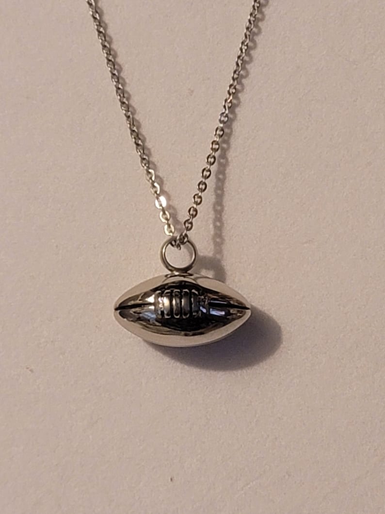 Pu&ograve; includere: Una collana con catena d'argento con un ciondolo a forma di pallone da calcio in argento.