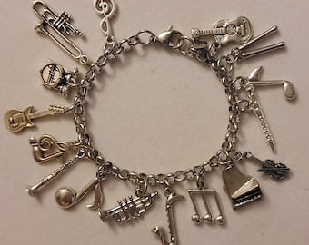 May include: A silver charm bracelet with various musical instrument charms, including a guitar, trumpet, saxophone, piano, drums, and a treble clef.