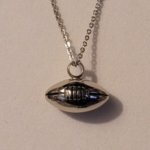 Pu&ograve; includere: Una collana con catena d'argento con un ciondolo a forma di pallone da calcio in argento.