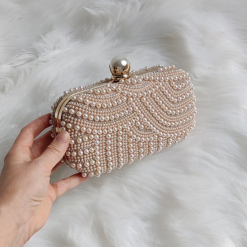 a hand holding a rose gold champagne pearl clutch bag for brides and wedding