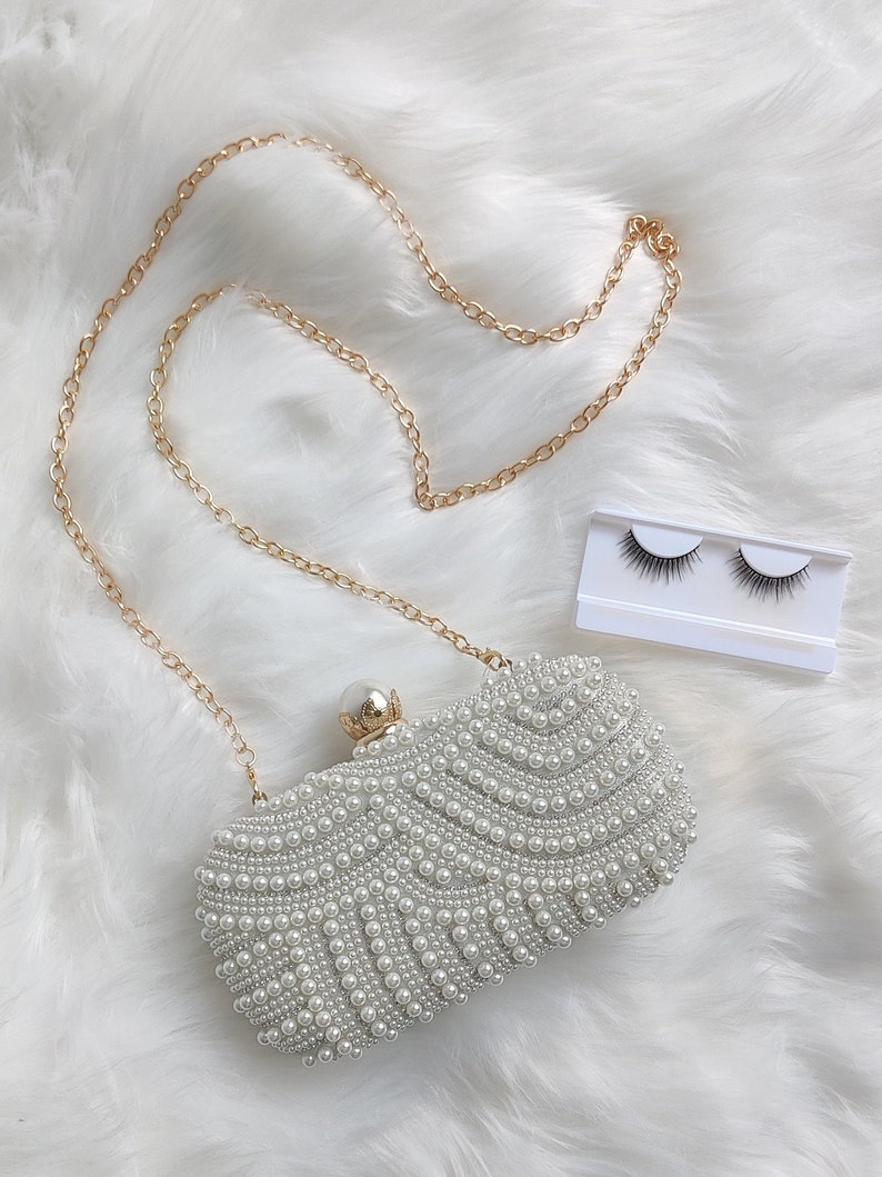 cream pearl bridal clutch and a pair of false eyelashes