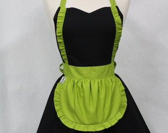May include: A black and lime green apron with a ruffled skirt and a sweetheart neckline. The apron has a lime green bib with a ruffled edge and a pocket.