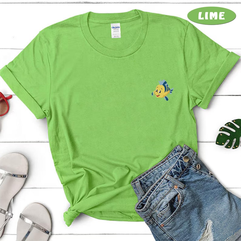 May include: Lime green t-shirt with a small embroidered cartoon fish. The shirt is paired with denim shorts. The word "LIME" is in a green oval in the upper right corner. The shirt is folded at the bottom.