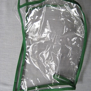 May include: Clear plastic hood with a green trim. The hood has a drawstring closure.