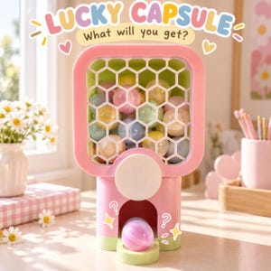 Può includere: Un distributore di capsule in plastica rosa e verde chiaro con un pannello frontale a nido d'ape riempito di capsule sferiche colorate. Il testo in alto recita LUCKY CAPSULE What will you get? con una capsula nel vassoio inferiore.