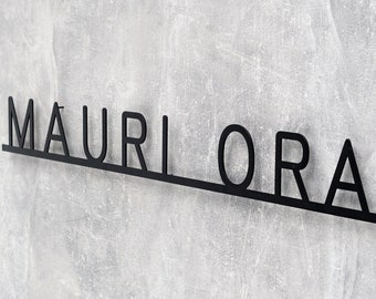 May include: Black metal sign with the name "MAURIORA" written in all caps.