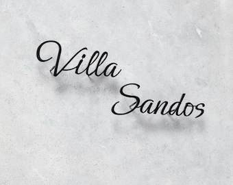 Puede incluir: Texto negro en cursiva sobre un fondo gris claro que dice "Villa Sandos". El texto está en una escritura elegante y fluida, probablemente para un letrero o elemento decorativo. El fondo tiene una apariencia texturizada y moteada.